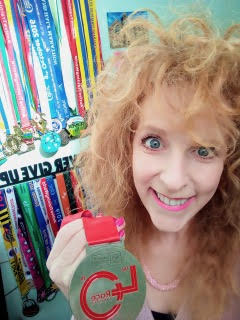 Sarah is smiling and holding up her marathon medal